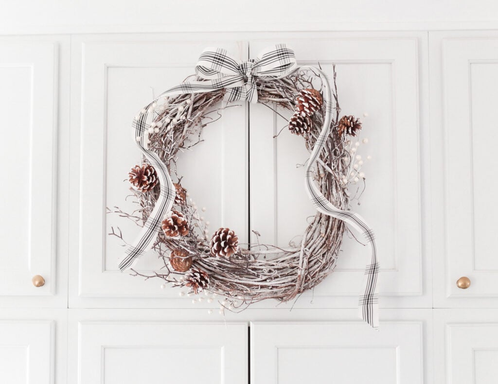 diy white flocked holiday wreath tutorial with pinecones bow